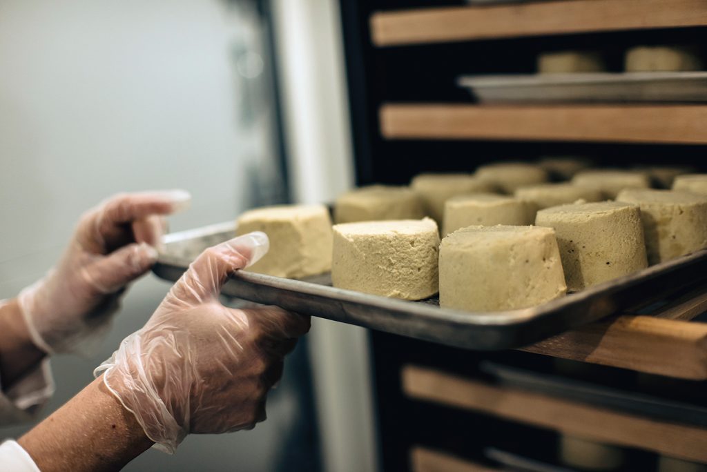 Hands preparing an artisan plant-based cheese product